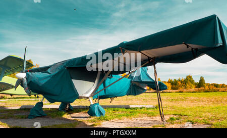 Blick auf klassische Flugzeug auf dem grasbewachsenen Flugplatz; Flugzeuge nach dem Flug mit Fällen auf Propeller und andere Elemente; Freizeit und Unterhaltung Stockfoto