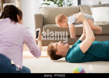 Mutter picturing Vater mit Baby von Smartphone Stockfoto