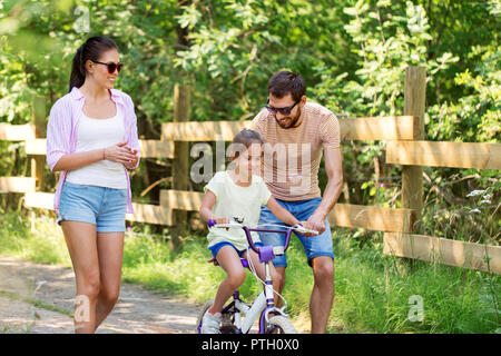 Kind mit Patenten lernen Fahrrad im Park zu fahren Stockfoto