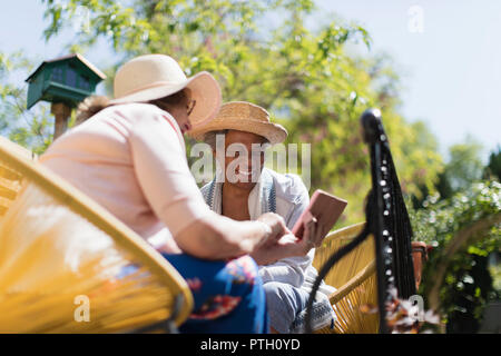 Ältere Frauen Freunde mittels Smart Phone auf der sonnigen Terrasse Stockfoto