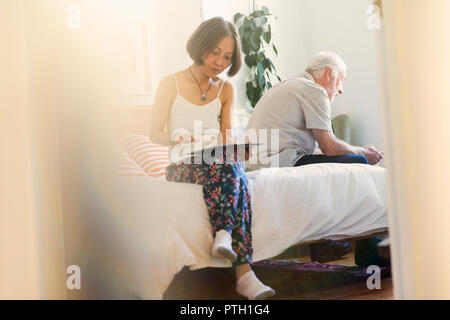 Senior Paar mit digitalen Tabletten im Schlafzimmer Stockfoto