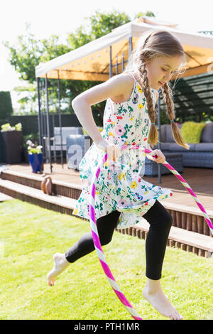 Mädchen spielen mit Kunststoff Hoop im sonnigen Hinterhof Stockfoto