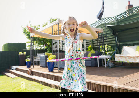 Portrait verspielten Mädchen spielen mit Kunststoff Hoop im sonnigen Hinterhof Stockfoto