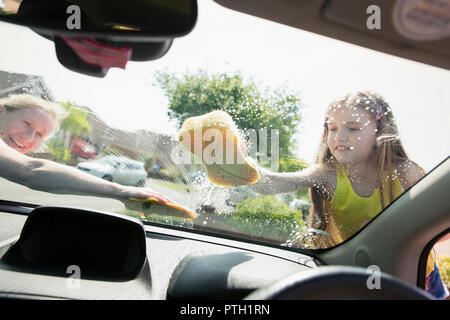 Mutter und Tochter waschen Auto Windschutzscheibe Stockfoto