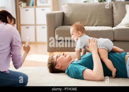 Mutter picturing Vater mit Baby von Smartphone Stockfoto