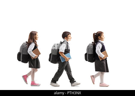 Volle Länge Profil Schuß von drei Schulkinder mit Rucksäcken und Bücher gehen auf weißem Hintergrund Stockfoto