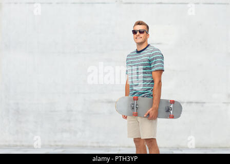 Lächelnden jungen Mann mit dem Skateboard über Weiß Stockfoto