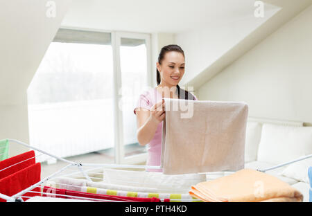 Frau, die Handtücher vom Wäscheständer zu Hause Stockfoto