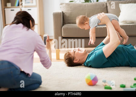 Mutter picturing Vater mit Baby von Smartphone Stockfoto