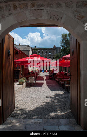 Mostar, Bosnien: ein Innenhof mit Tischen im Freien, eine Bar und einen Palast während des bosnischen Krieges bombardiert (1992-1995) im Hintergrund Stockfoto