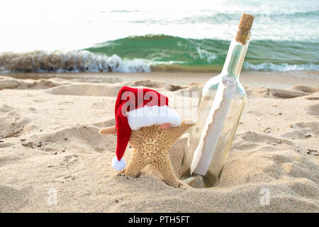 Seesterne in Strand Sand mit Santa Hut und Flaschenpost Stockfoto