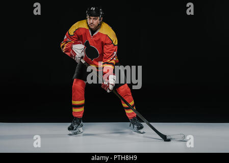 Volle Länge Blick auf Professionelle young Ice Hockey Player spielen Hockey auf Schwarz Stockfoto