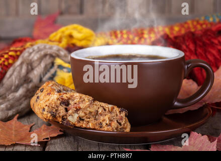 Nahaufnahme einer dampfenden Tasse Kaffee und Rosinen Cookies mit Herbst Blätter und bunte Decke im Hintergrund Stockfoto