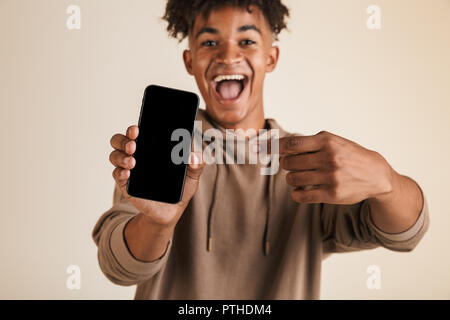 Porträt einer positiven jungen afro-amerikanische Mann in Hoodie isoliert gekleidet, zeigen auf Blank Screen Handy Stockfoto