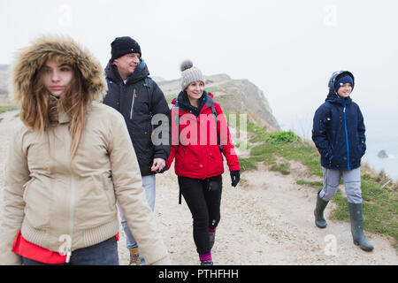 Familie in warme Kleidung Wandern auf verschneiten Winter Cliff Path Stockfoto