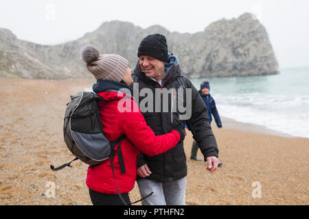 Zärtlich, glückliches Paar in warme Kleidung auf verschneiten Winter Strand Stockfoto