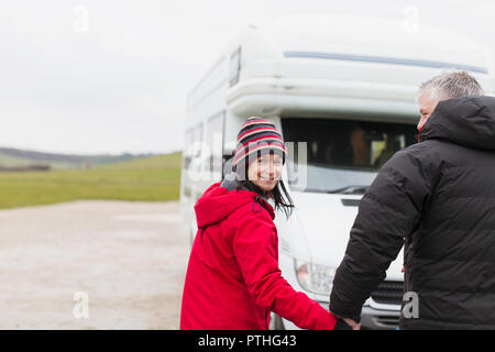 Portrait lächelndes Paar in warme Kleidung, Hände halten außerhalb Motor home Stockfoto