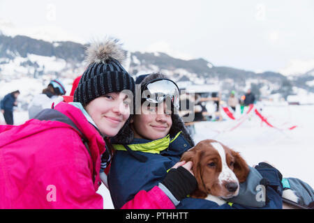 Porträt Bruder und Schwester mit Hund auf Skipiste Stockfoto