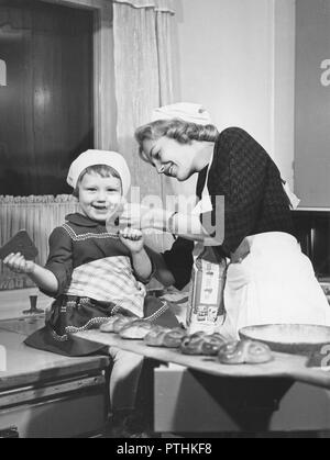 Weihnachten in den 1950er Jahren. Marianne Lestander, die für diese Jahre Stockholms Lucia gewählt ist, wird zusammen backen mit einem kleinen Mädchen. Schweden 1959 Stockfoto