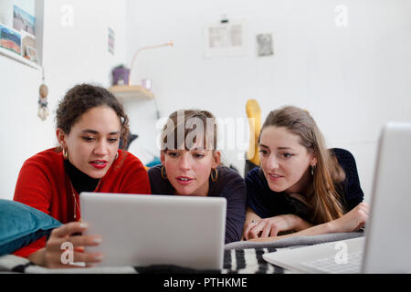 Junge Frauen Freunde gemeinsame Nutzung digitaler Tablet auf dem Bett Stockfoto