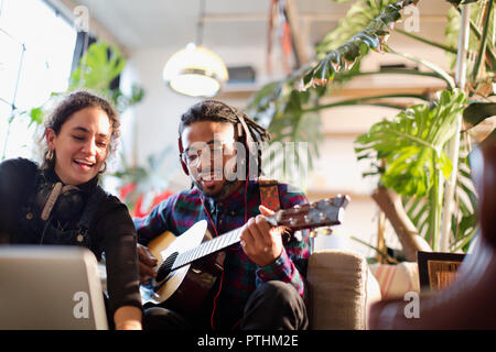 Junger Mann und Frau Aufnehmen von Musik, Gitarre spielen in der Wohnung Stockfoto