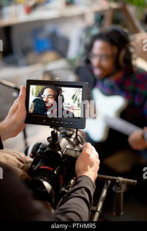 Videographer Filmen junge männliche Musiker singen und Gitarre spielen Stockfoto