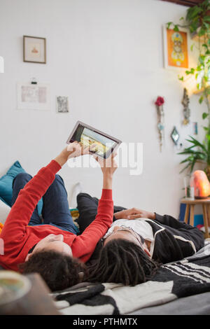 Junges Paar, entspannend, mit digitalen Tablet auf dem Bett Stockfoto