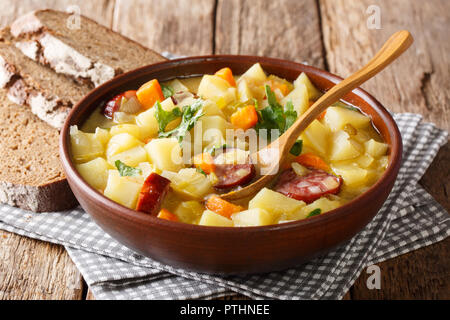 Dicke Kartoffelsuppe mit Würstchen und Petersilie in einer Schüssel mit Brot close-up auf dem Tisch. Horizontale Stockfoto