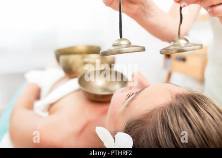 Nahaufnahme einer jungen Frau, die sich einer Klangtherapie mit Klangschalen, Zimbeln Stockfoto