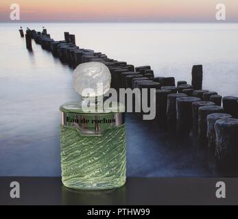 Eau de Rochas, Duft für Damen, große Parfüm Flasche vor dem Bild einer groyne im Meer Stockfoto