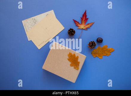 Herbst Komposition. Geschenkbox, Herbstblätter, alte Grußkarten auf violett unterlegt. Stockfoto
