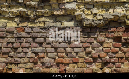 Hintergrund von einem alten zerstörten Mauer aus roten und gelben Backstein Stockfoto