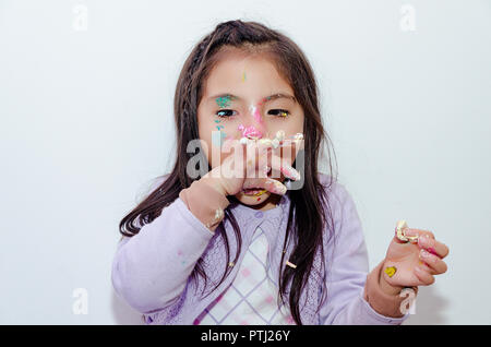 Süße kleine Mädchen mit Kuchen auf Ihrem Gesicht für ihren Geburtstag verschmiert Stockfoto