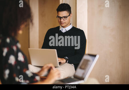 Kaufmann und Frau arbeiten an ihren Laptops sitzen auf Stühlen im Amt. Creative Business Mannschaftskameraden auf Laptops im Büro. Stockfoto