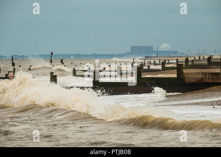 Wellen brechen am Strand und buhnen in Southwold mit Sizewell Kernkraftwerk in der Ferne. Stockfoto