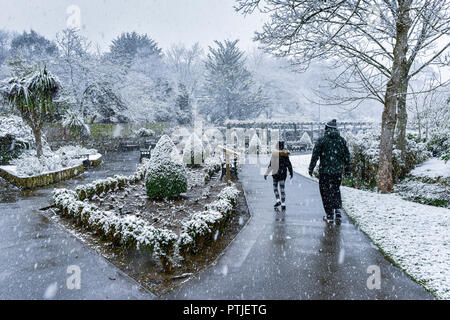 Menschen zu Fuß durch eine schwere Schneefälle in Trenance Park in Newquay in Cornwall. Stockfoto