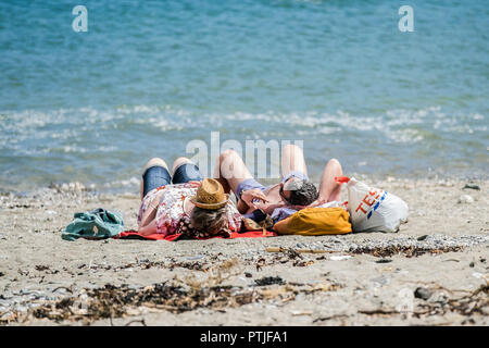 Urlauber Sonnenbaden am Strand im Trebah Garten in Cornwall. Stockfoto