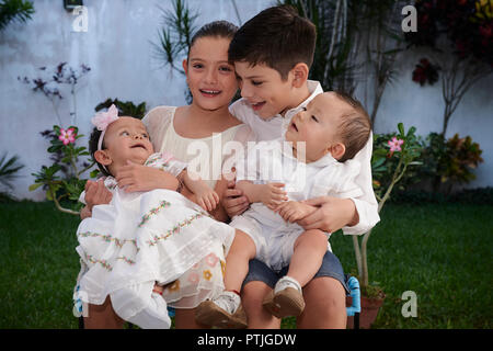 MERIDA, Yuc/MEXIKO - November 13, 2017: Bruder und Schwester halten Sie Ihr Baby twin Cousins vor der Taufe in der Kirche. Stockfoto