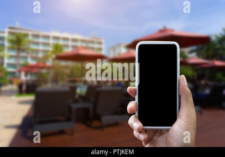 Die Hand des Mannes zeigt Mobile Smartphone in vertikaler Position mock up Vorlage und verschwommenes Hotel Hintergrund für Ihr Buch Hotel bussiness. Stockfoto