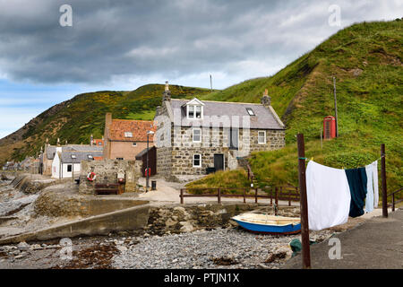 Einzelne Zeile von Häusern der Crovie Küstenfischerei Dorf auf Gamrie Bucht Nordsee Aberdeenshire Schottland Großbritannien mit roten Telefonzelle und Waschen auf Linie Stockfoto