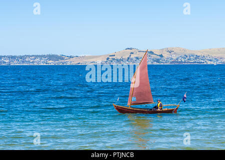 Derwent River Hobart, Tasmanien, Australien - 6. Januar 2017: Klassische Klinker Jolle mit roten Segeln auf blauem Wasser weg Sandy Bay Beach Stockfoto