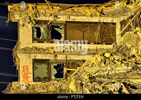 Die letzte Mauer eines Bürogebäudes still mit Graffiti und zerbrochene Fenster. Einige Stromleitungen auf dem Hintergrund eines apokalyptischen Foto. Stockfoto