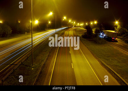 Neblige Nacht auf der Autobahn mit einigen Autos vorbei, leichte Wanderwege. Stockfoto