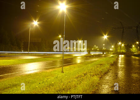 Leere Autobahn an regnerischen Nacht mit wenigen Autos vorbei, leichte Wanderwege. Stockfoto