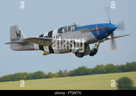 North American P-51 Mustang Jagdflugzeug bei einer Airshow Flying. P-51 C aus einfahren Fahrwerk Räder mit Cambridgeshire Landschaft Stockfoto