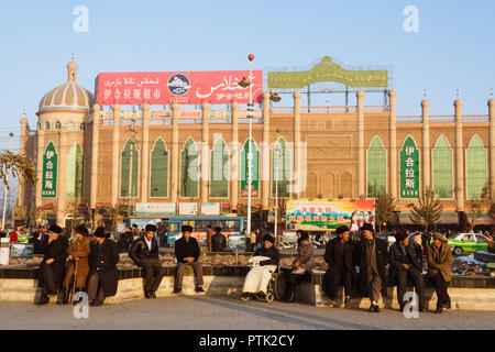 Kashgar, Xinjiang, China: Uiguren Männer sitzen und plaudern außerhalb der Ihlas Shopping Mall in Kashgar. Stockfoto