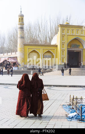 Kashgar, Xinjiang, China: Zwei Uigurischen verschleierte womenwalk Vergangenheit der gelben Fliesen- Id kah-Moschee (1442), die geistige und physische Herz der Stadt. Stockfoto