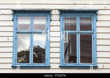 Zwei blaue Fenster nebeneinander auf einer rauhen und unebenen Holzwand. Abstrakte close-up Stockfoto