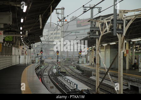 Bahnhof in Tokio: eine perspektivische Ansicht der Wicklung Anschlüssen, Kabeln und der städtischen Gebäude, vom Bahnsteig gesehen, an einem grauen, regnerischen Tag Stockfoto