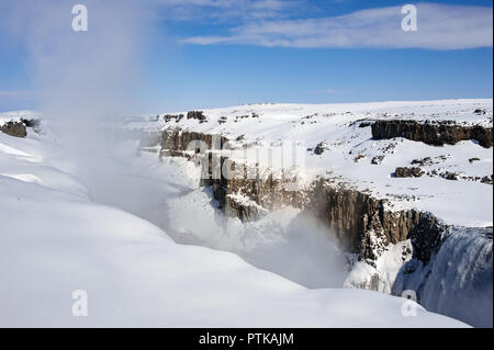 Winter, verschneite Landschaft, Wasserfall Dettifoss, Island. Spray füllt die Luft über dem Wasserfall und Sonnenlicht reflektiert über die Seiten der Schlucht Stockfoto